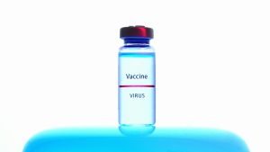 Close-up of a vaccine vial against a bright blue background, symbolizing medical research.