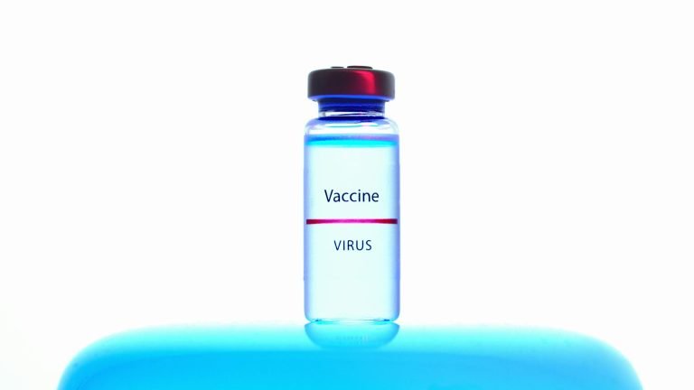 Close-up of a vaccine vial against a bright blue background, symbolizing medical research.